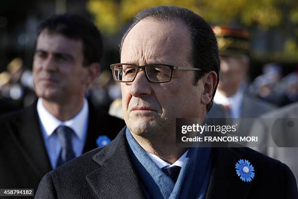 French President Francois Hollande , and Prime minister Manuel Valls, both wearing a bluberry flower as a tribute to WWI French soldiers, stand at...