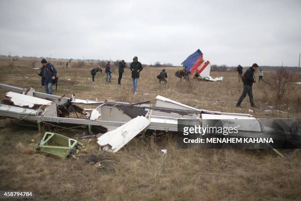 Journalists look at parts of the Malaysia Airlines plane Flight MH17 as Dutch investigators arrive at the crash site near the Grabove village in...