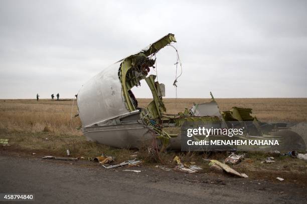 Journalists walk behind parts of the Malaysia Airlines plane Flight MH17 as Dutch investigators arrive near at the crash site near the Grabove...