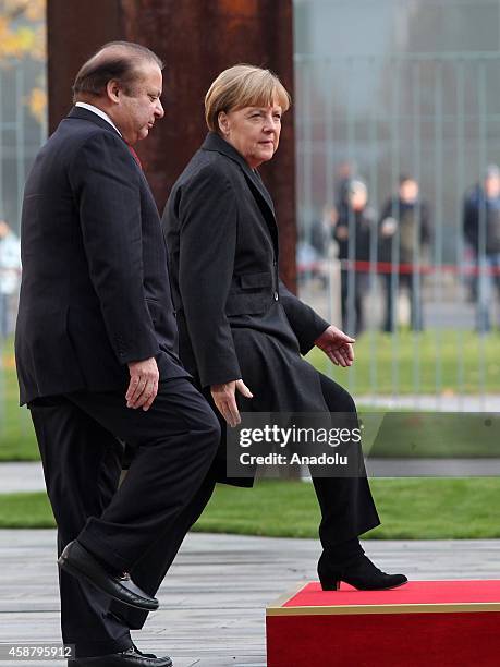 Germany's Chancellor Angela Merkel and Pakistan's Prime Minister Nawaz Sharif walk together as honor guards stand still in front of the Prime...