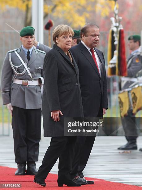 Germany's Chancellor Angela Merkel and Pakistan's Prime Minister Nawaz Sharif walk together as honor guards stand still in front of the Prime...