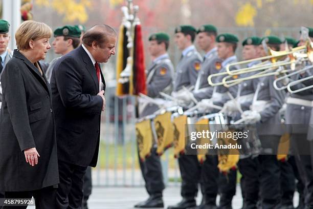 Germany's Chancellor Angela Merkel and Pakistan's Prime Minister Nawaz Sharif salute together as honor guards stand still in front of the Prime...