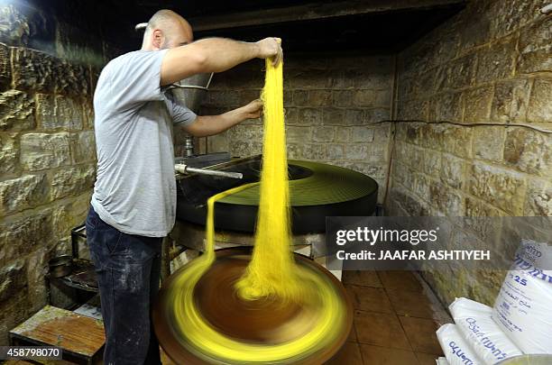 Palestinian cook prepares the typical Palestinian sweet Kanafeh, a Levantine cheese pastry soaked in a sweet sugar-based syrup, in the West Bank City...