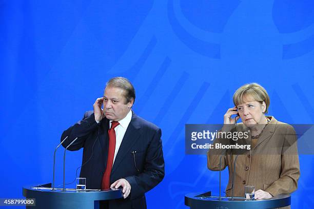 Nawaz Sharif, Pakistan's prime minister, left, adjusts his earpiece as he stands beside Angela Merkel, Germany's chancellor, during a news conference...