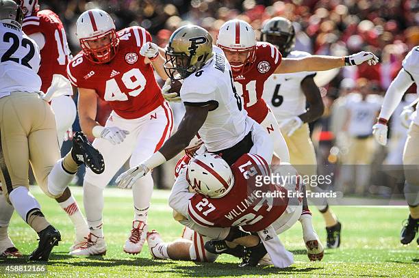 Running back Raheem Mostert of the Purdue Boilermakers is wrapped up by defensive back Kieron Williams and linebacker Josh Banderas of the Nebraska...