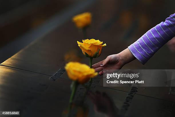 Child reaches out to touch a flower adorning the 9/11 Memorial on the name of a veteran killed on September 11, 2001 for Veterans Day on November 11,...