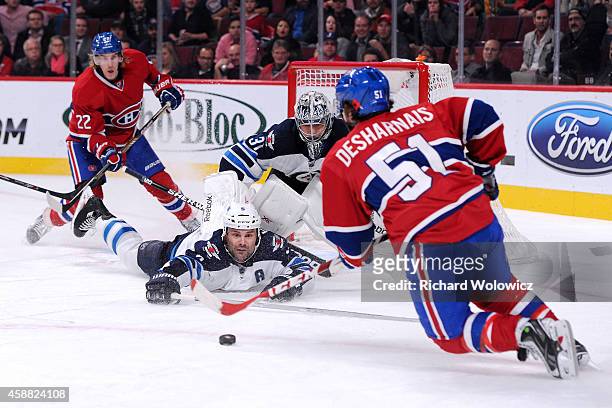 David Desharnais of the Montreal Canadiens stick handles the puck in front of Mark Stuart and Ondrej Pavelec of the Winnipeg Jets during the NHL game...