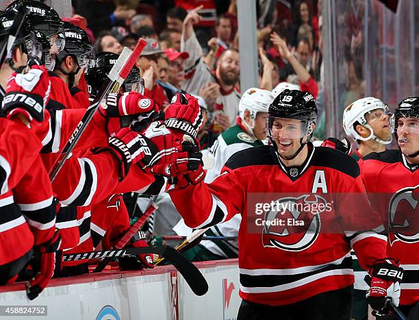 Travis Zajac of the New Jersey Devils celebrates with teammates on the bench after he scored an empty net goal in the third period against the...