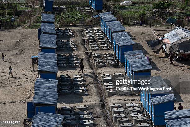 People walk past makeshift latrines at the Mayebon IDP camp where registration has taken place forcing the residents of the camp to list themselves...