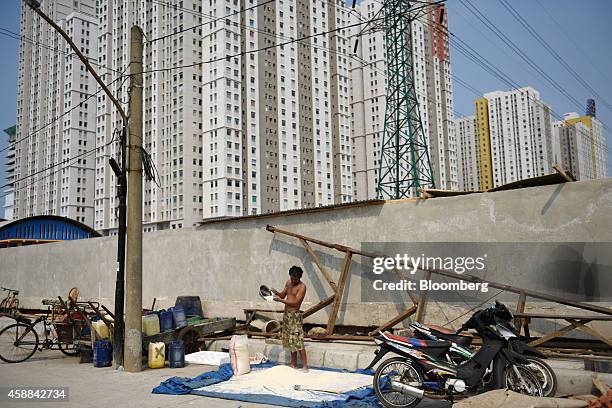 Man spreads rice grains on a sheet by the side of a road near the Green Bay Pluit residential and commercial project, developed by PT Agung Podomoro...