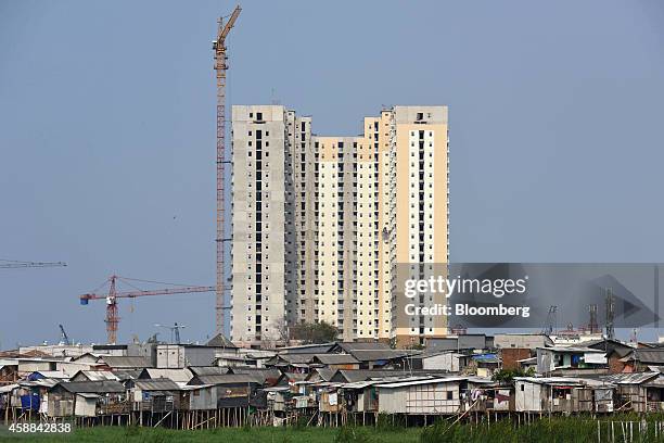 Shanty houses perched on stilts stand in front of high-rise residential buildings under construction near the Pluit Dam area of North Jakarta,...