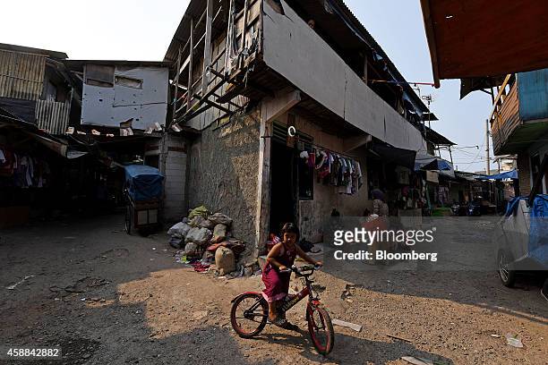 Girl rides a bicycle in front of shanty houses near the Pluit Dam area of North Jakarta, Indonesia, on Wednesday, Nov. 5, 2014. Jakarta, a former...