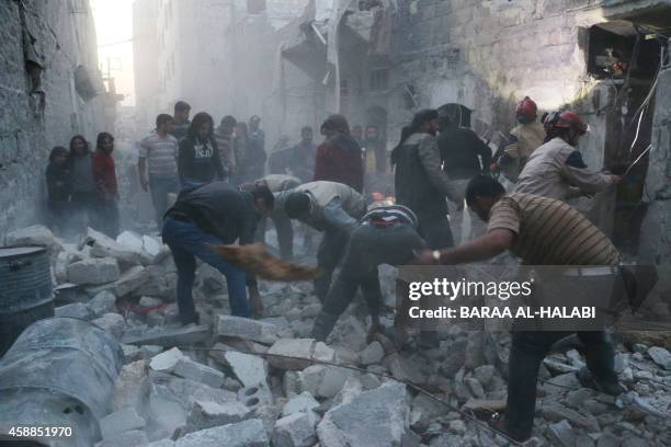 Syrian Civil Defence workers and pedestrians clear debris after an alleged air strike by Syrian government forces in the Bab al-Nairab neighboured...