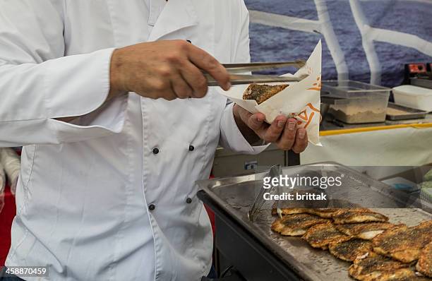 preparing fish burger with baltic herrring at fair in stockholm - food stall stockfoto's en -beelden