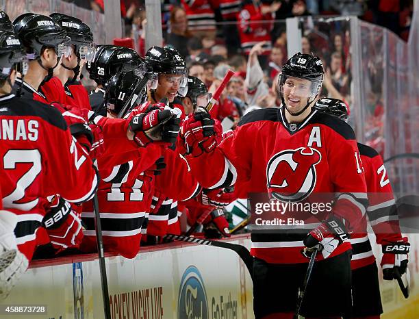 Travis Zajac of the New Jersey Devils is congratulated by teammates on the bench after he scored an empty net goal in the third period against the...