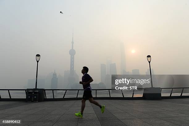 This photo taken on November 12, 2014 shows a resident exercising amid heavy smog on the Bund in Shanghai as the local meteorological department...