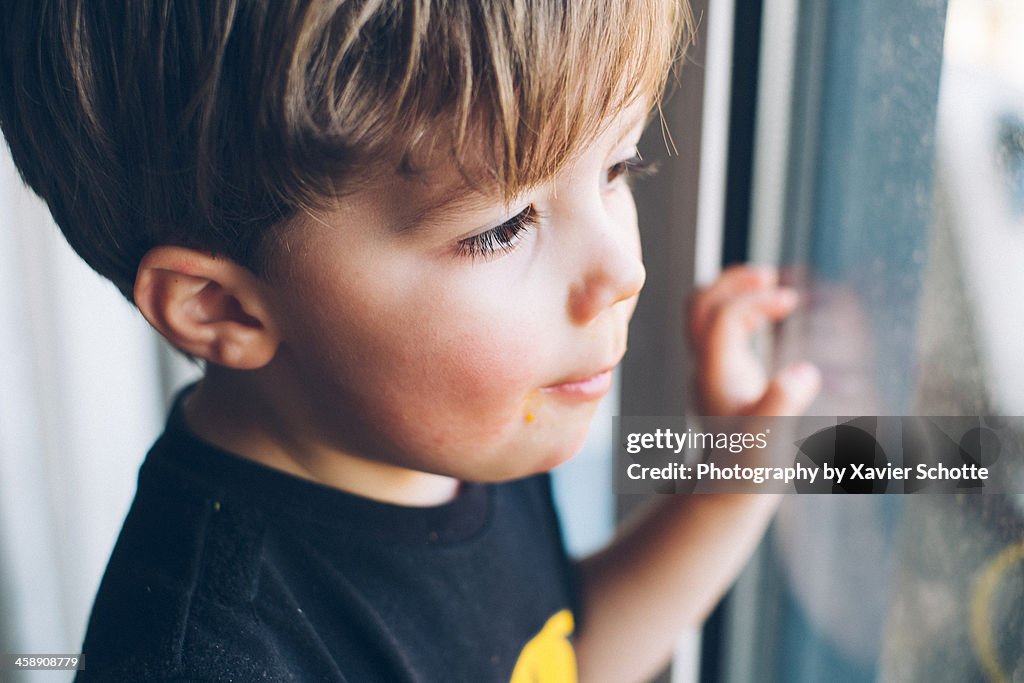 Young boy looking trhough the window