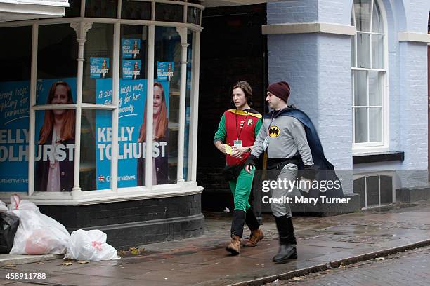 Two men dressed as Batman and Robin walk past Conservative party posters for candidate Kelly Tolhurst, as they distribute leaflets for her campaign...