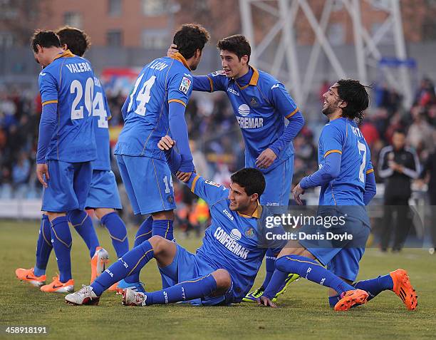 Lisandro Lopez of Getafe CF is helped up by Pedro Leon while Angel Lafita looks on after Lopez scored Getafe's 2nd goal during the La Liga match...