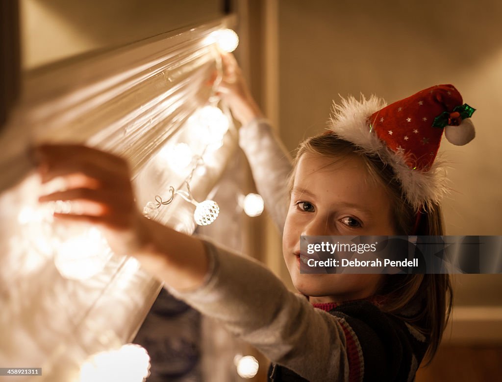 Young girl hanging Christmas fairy lights