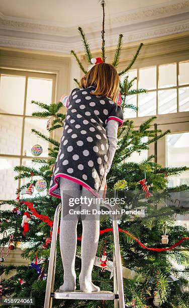 young girl up a ladder decorating christmas tree - bent ladder stock pictures, royalty-free photos & images