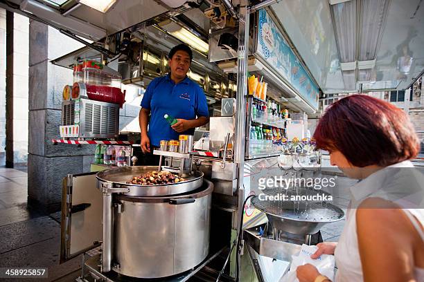woman buying roasted chestnuts in fast food kiosk, milan, italy - nutella stockfoto's en -beelden