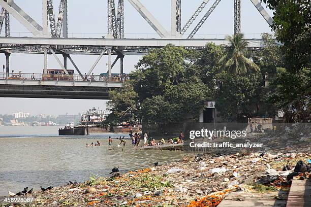 people bathing underneath howrah bridge - kolkata city stock pictures, royalty-free photos & images