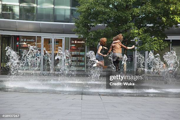 deux jeunes filles sautant dans la fontaine - dos humain photos et images de collection
