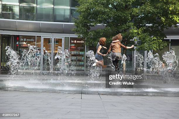 two young girls jumping in the fountain - human back stock pictures, royalty-free photos & images