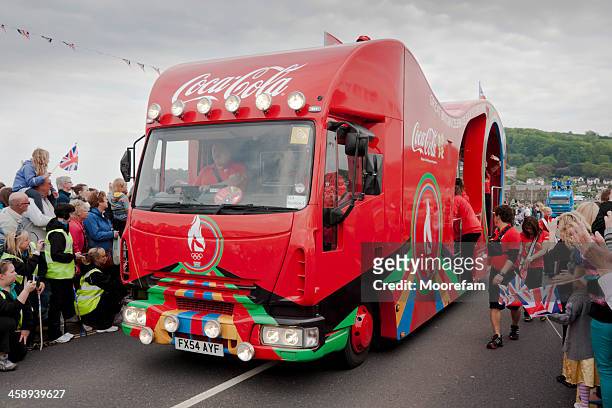 coca cola lorry in procession with the olympic flame runners - sponsor stock pictures, royalty-free photos & images
