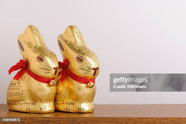 dos lindt pascua oro de conejos en el estante - conejo de pascua fotografías e imágenes de stock