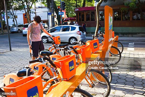 young man renting a bicycle - bicycle parking station stock pictures, royalty-free photos & images