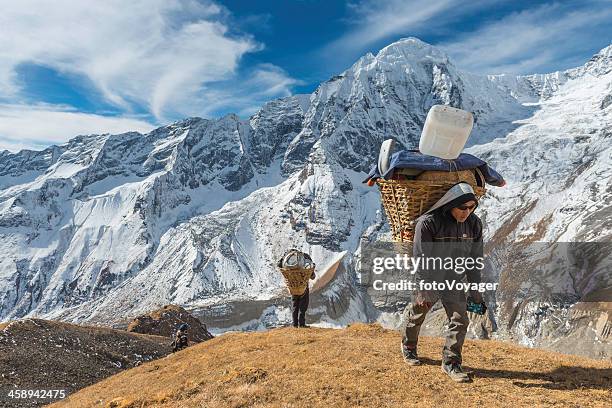 sherpa porter carrying expedition load high in himalaya mountains nepal - sherpa nepal stock pictures, royalty-free photos & images