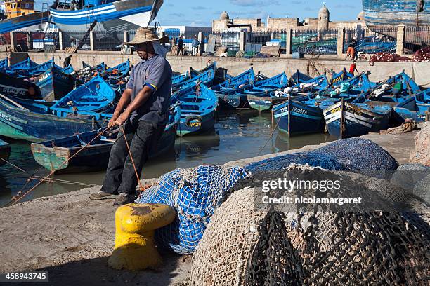 essaouira, morocco:  fisherman pulling his boat in - nicolamargaret stock pictures, royalty-free photos & images