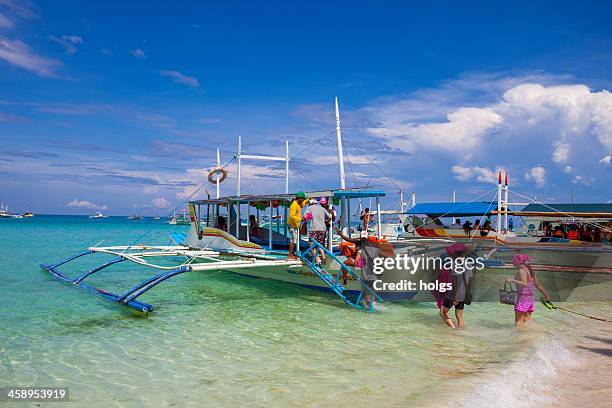 passengers board an outrigger boat at boracay, philippines - boracay beach stock pictures, royalty-free photos & images