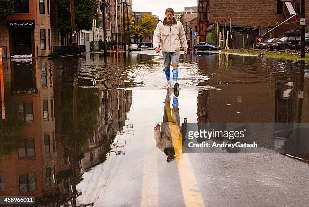 man walking on the flooded street after hurricane sandy landfall - hurricane sandy bildbanksfoton och bilder