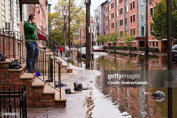 hurrican sandy: man talking on the phone near flooded street - flood city stock pictures, royalty-free photos & images