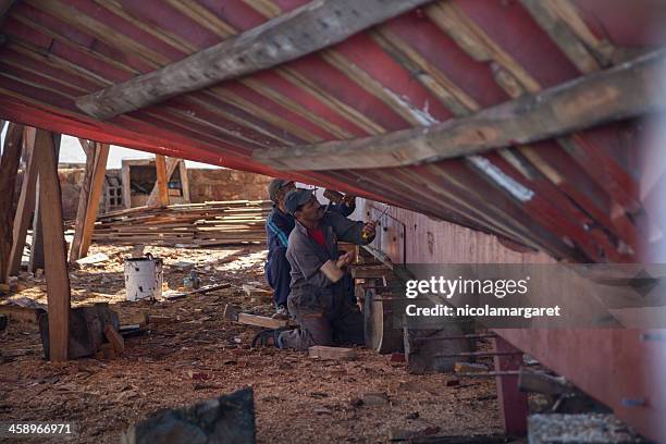 shipbuilding: two men using chisels on boat hull - nicolamargaret stock pictures, royalty-free photos & images