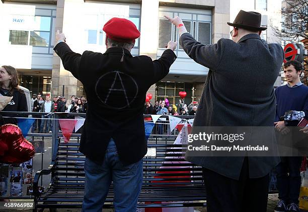 Fans Mark Adams and Lawrence Harman wave at fansby the memorial bench for the late Rik Mayall is unveiled on November 14, 2014 in London, England.