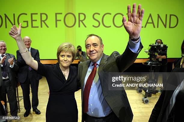 Scotland's First Minister Alex Salmond waves together with new party leader Nicola Sturgeon after he delivers his final speech as the leader of the...