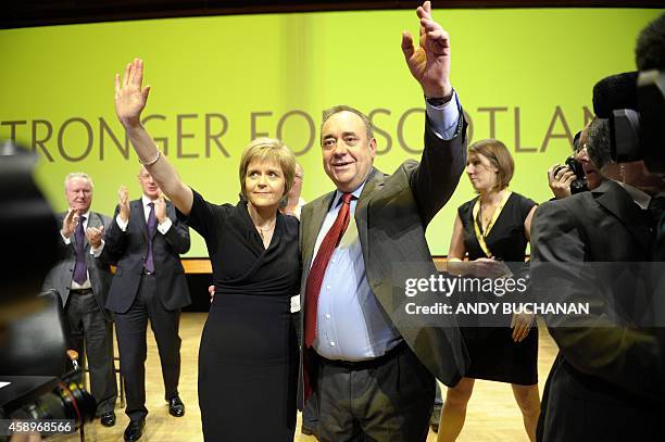Scotland's First Minister Alex Salmond waves together with new party leader Nicola Sturgeon as he delivers his final speech as the leader of the...