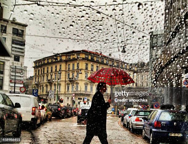 uomo con ombrello sotto la pioggia strada di attraversamento di milano, italia - tempo atmosferico foto e immagini stock