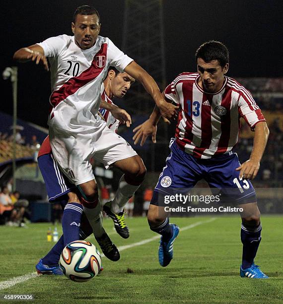 Luis Alberto Ramirez of Peru struggles for the ball with Cristian Riveros and Junior Alonso of Paraguay during an international friendly match...