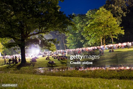 People walking through park after concert at night People walking through park after concert at night