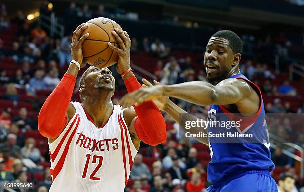 Dwight Howard of the Houston Rockets drives with the basketball against Henry Sims of the Philadelphia 76ers during their game at the Toyota Center...