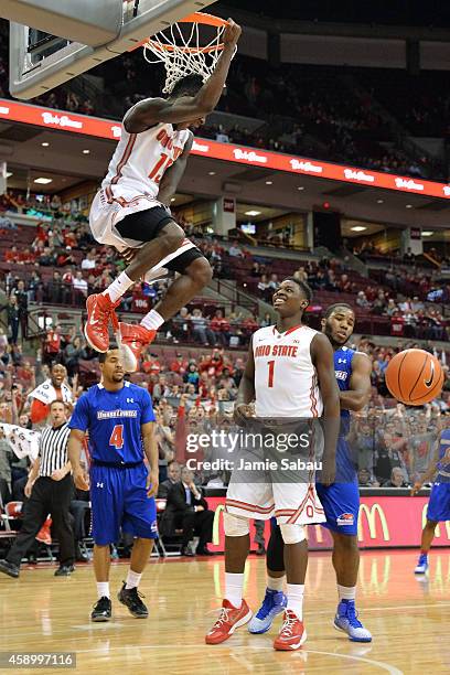 Kam Williams of the Ohio State Buckeyes celebrates his alley-oop dunk in the second half against the Massachusetts-Lowel River Hawks with teammate...