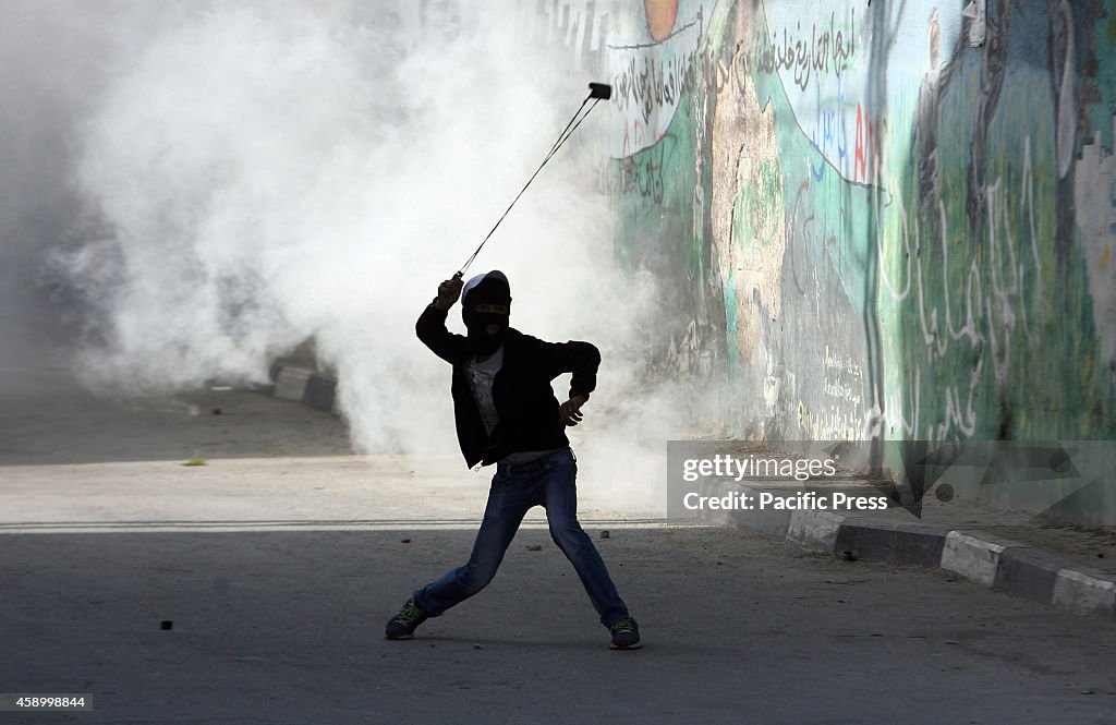 Palestinian youth hits stones at the Israeli army during...