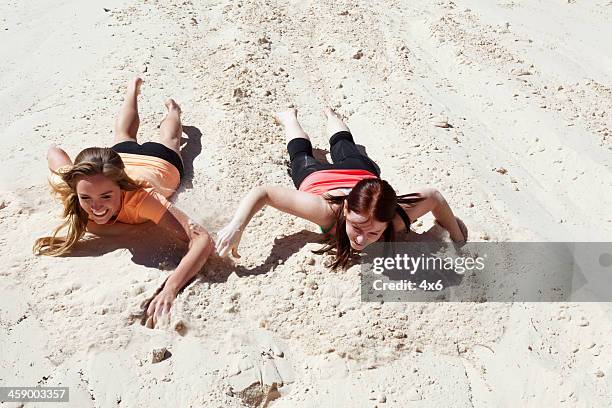 two young adult females sliding down sand - st george utah stock pictures, royalty-free photos & images