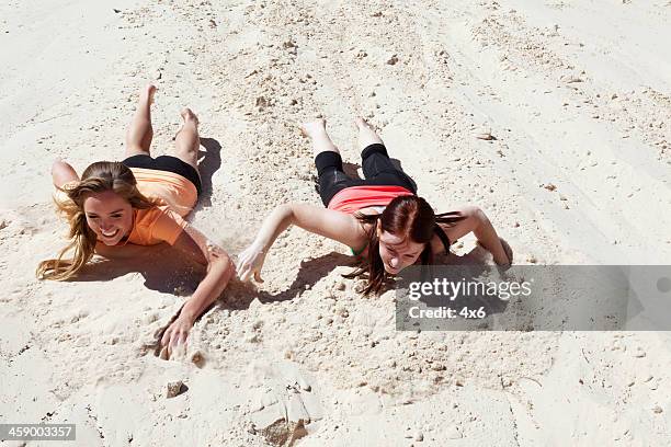 two young adult females sliding down sand - st george utah 個照片及圖片檔