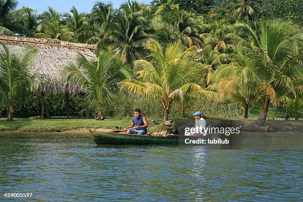 guatemalan men sailing along the rio dulce in guatemala. - livingston guatemala stock pictures, royalty-free photos & images